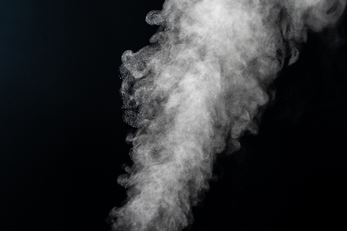 Smoke pours out over a black background.